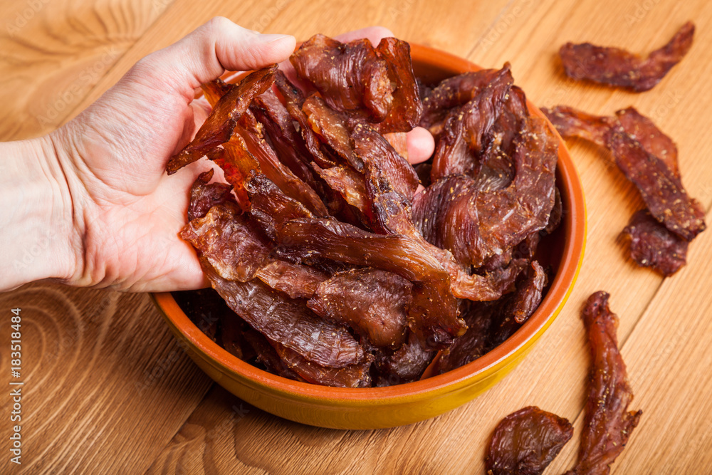 Homemade chicken jerky in a ceramic bowl. Delicious dried chicken close-up Homemade chicken jerky in a ceramic bowl. Delicious dried chicken close-up