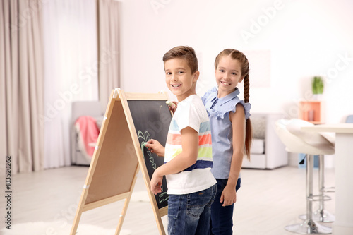 Little boy with sister drawing on chalkboard at home