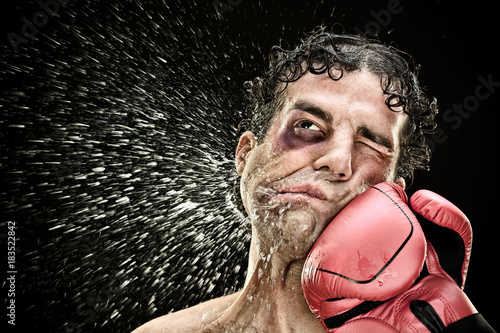 silly boxer man takes a punch in the face isolated on black.funny concept portrait photo