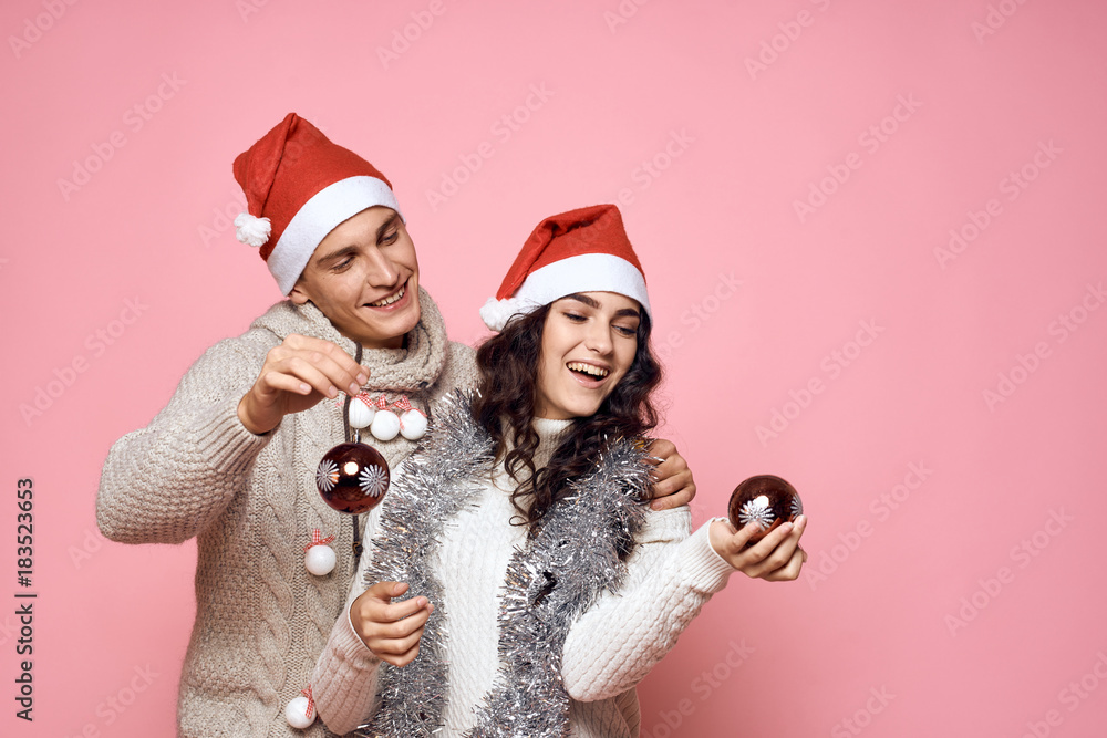 man and woman smiling and holding glass balls in hands, light pink background, new year, emotions man and woman smiling and holding glass balls in hands, light pink background, new year, emotions