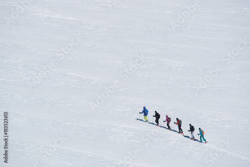 group of people exploring glacier or snowy land walking with snowshoes. Europe Alps Mont Blanc massif mount. Winter sunny day, snow, wide shot.Exploring and travelling