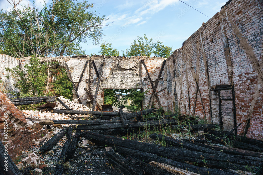 Old abandoned ruined building with burned logs of wood