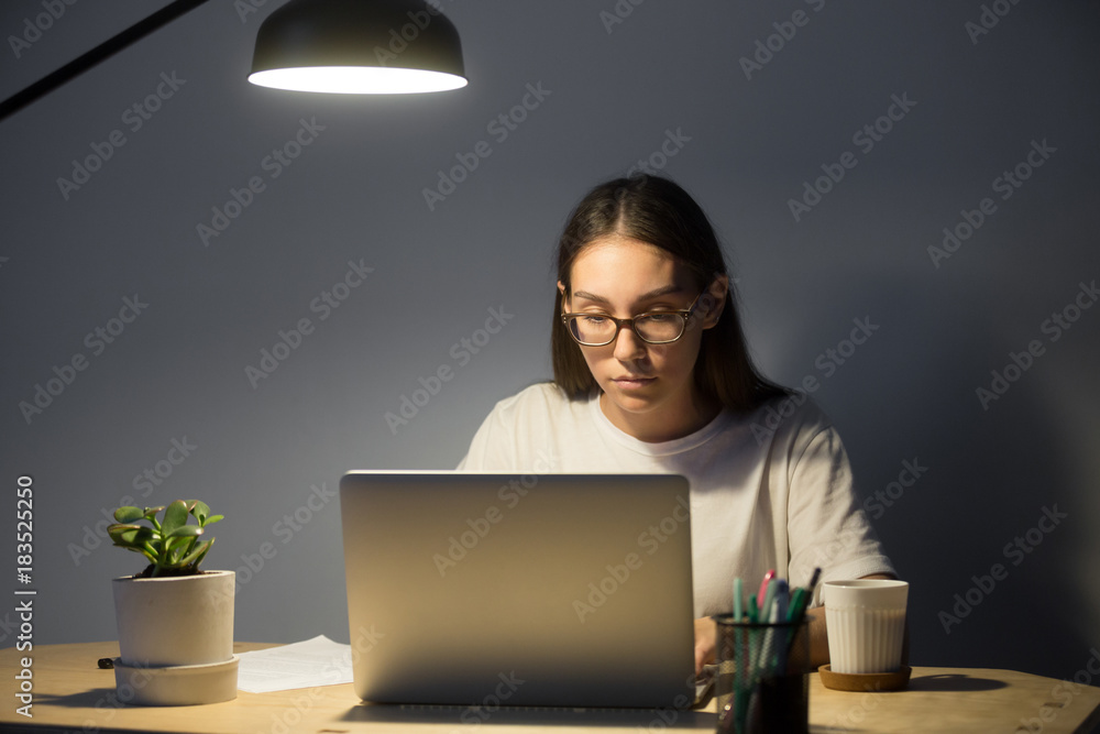 Φωτογραφία Portrait of millennial businesswoman in glasses looking at laptop and working at night