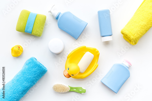 Bath accessories for kids. Yellow rubber duck, soap, sponge, brushes, towel on white background top view