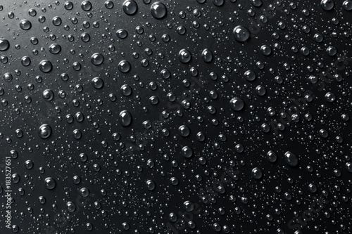 Water drops on black surface, abstract background.