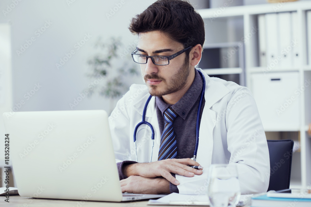 Portrait of doctor working on computer in medical office Portrait of doctor working on computer in medical office