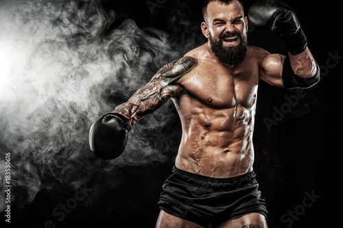 Sportsman muay thai boxer fighting on black background with smoke. Copy Space. Sport concept.