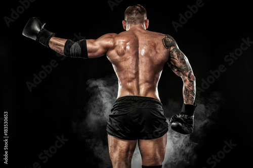 Fototapeta Sportsman muay thai boxer fighting on black background with smoke