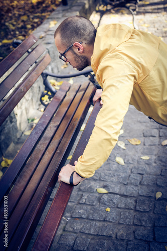 Man working pushups on park bench.