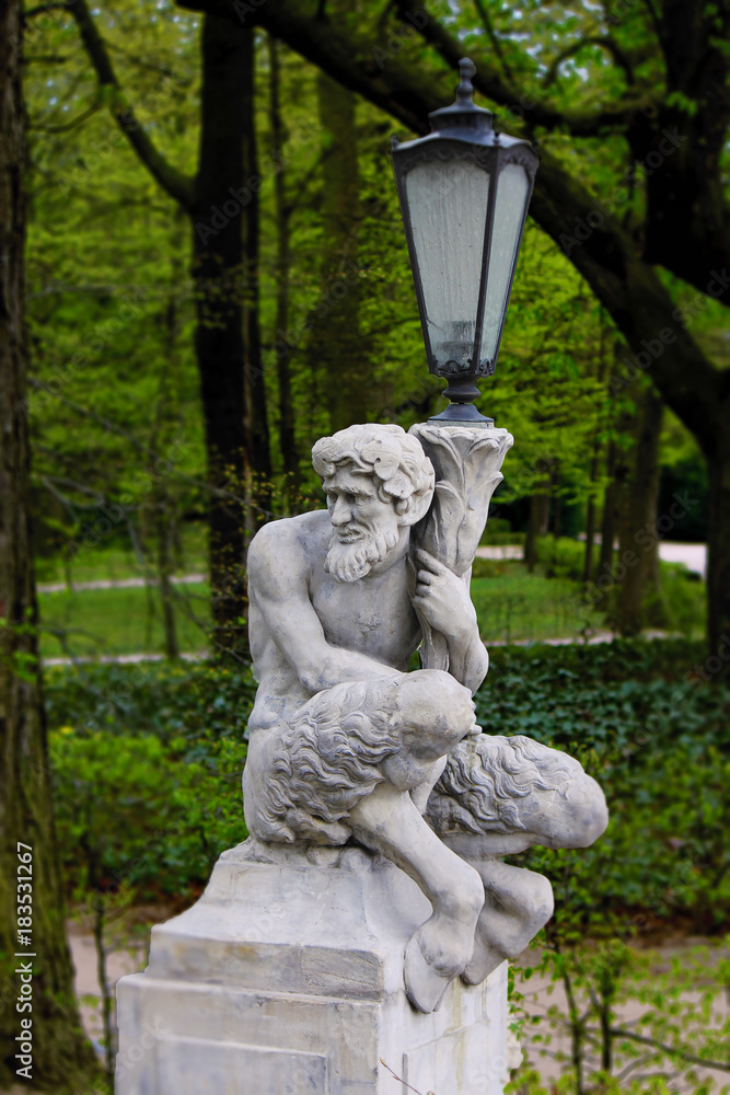 Fototapeta premium Baroque Statue of a Satyr or Faun holding a Lantern in a Park