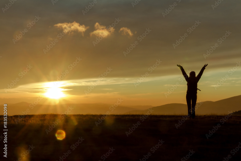 woman standing with her back on sunset