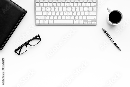Stylish office desk. Trendy monochrome. Black notebook, glasses, pen and coffeee on white background top view copyspace
