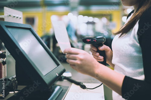 Young woman hands scaning / entering discount / sale on a receipt, touchscreen cash register, market / shop (color toned image) photo
