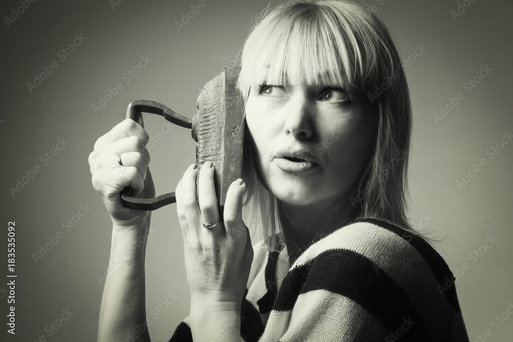 Obraz premium Beautiful middle-aged woman, blonde, with iron in hands