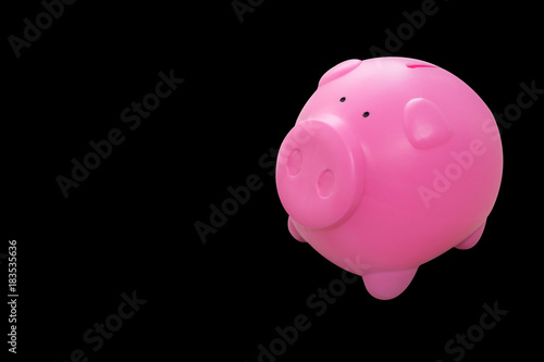Pink piggy saving money isolated on black background.