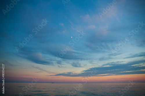 Sea and sky at sunset. Beautiful landscape. month in the sky and boat in the distance