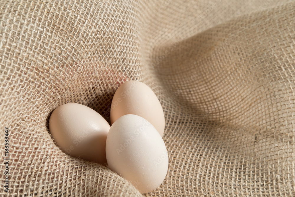 three chicken eggs on a linen burlap three chicken eggs on a linen burlap