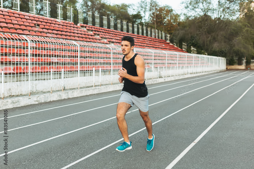 Young athletic man running on the stadium in the morning Young athletic man running on the stadium in the morning