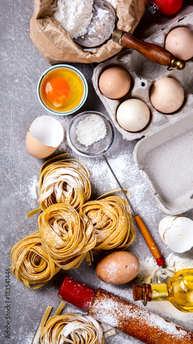 Fresh Ingredients for Cooking Traditional Italian Pasta Tagliatelle.Flour,Eggs,olive oil on a grey stone Background.Copy space for Text. selective focus.