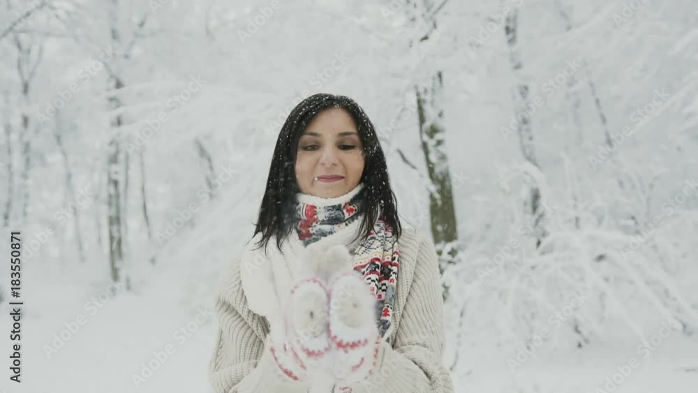 Close-up of a young woman who walks in a snow-covered forest and clapping in the palm of his hands shaking the snow from the mitts Close-up of a young woman who walks in a snow-covered forest and clapping in the palm of his hands shaking the snow from the mitts