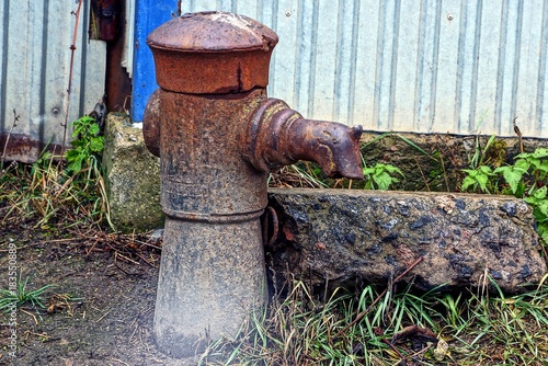 старая железная колонка для воды на улице у забора