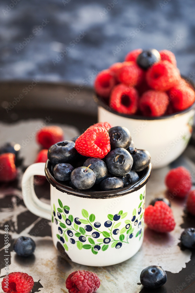 Fresh ripe blueberry and raspberry in mugs Fresh ripe blueberry and raspberry in mugs