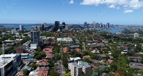 Lower North Shore residential suburbs with small houses and green streets towards Sydney Harbour and city CBD landmarks and high-rise towers.
 photo