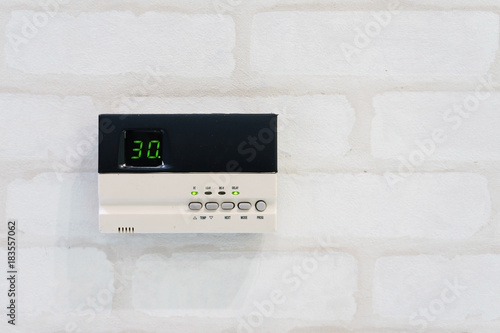 Modern programming thermostat in front of white brick wall with copyspace and text