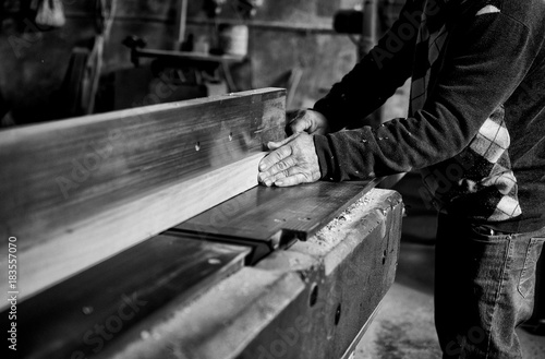 Falegname mentre lavora il legno nella sua fabbrica photo