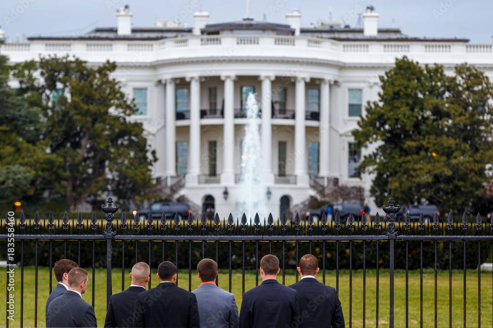 Young men in jackets are standing in front of the White House in Washington