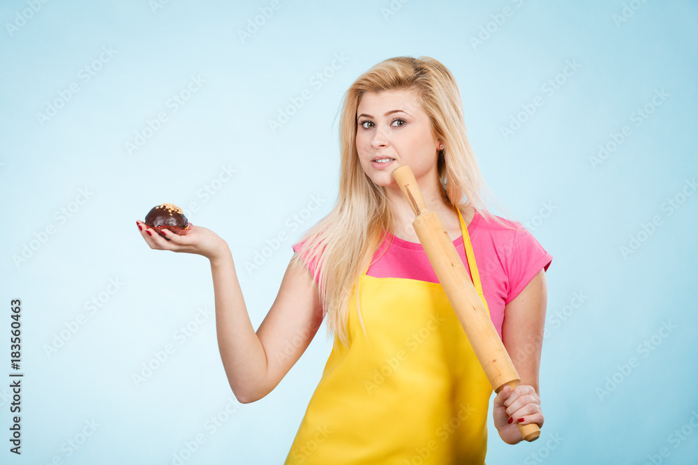 Woman holding cupcake and rolling pin wearing apron Woman holding cupcake and rolling pin wearing apron