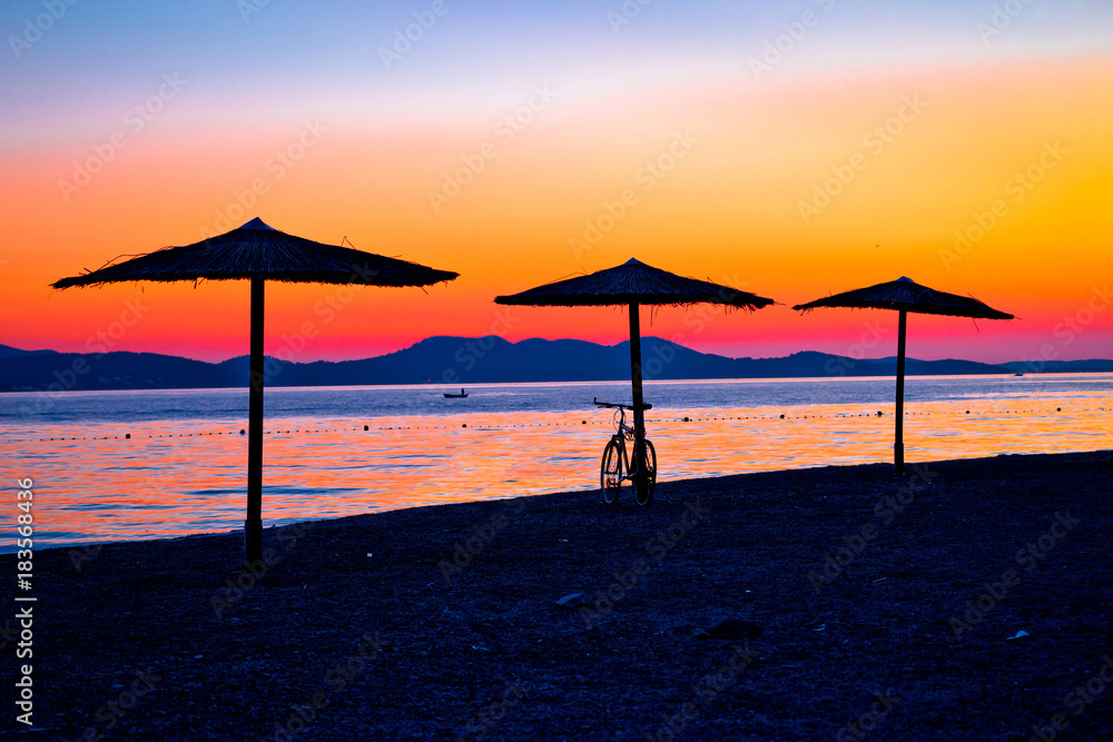 Beach and parasols on colorful sunset view