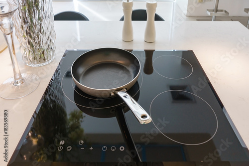 Quadro em tela Frying pan on modern black induction stove, cooker, hob or built in cooktop with