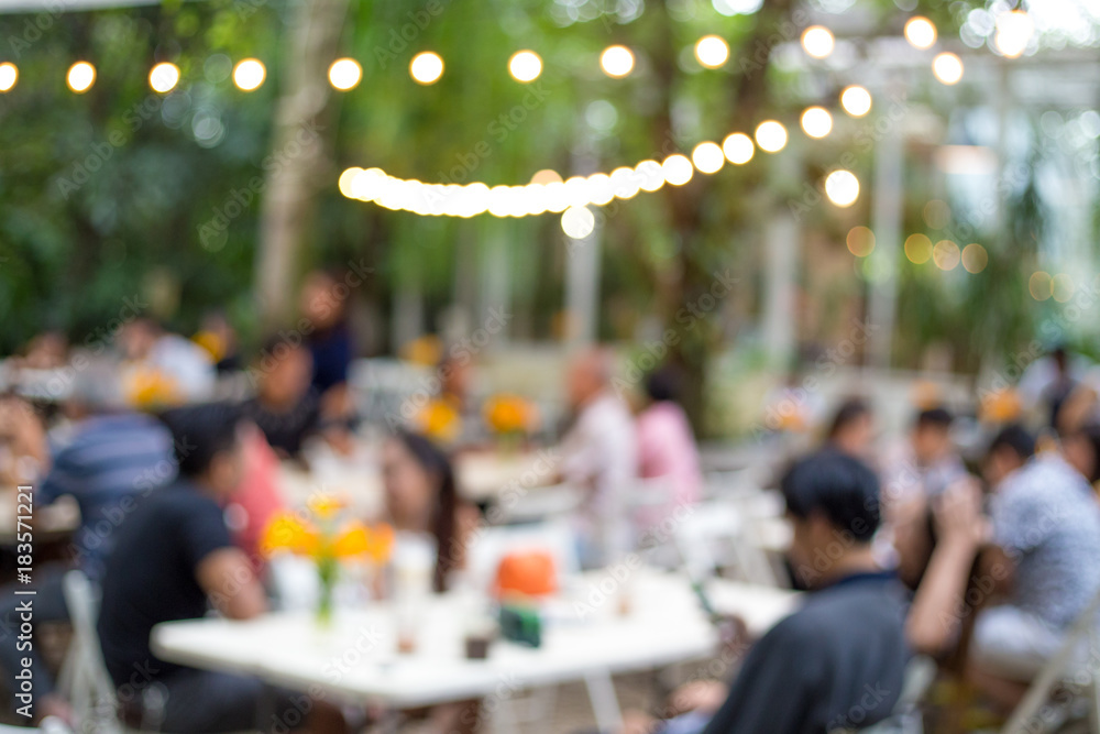 Blur the cafe in the park with people.
