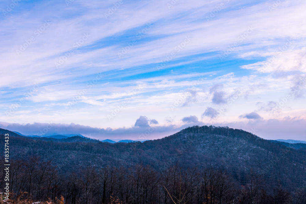 Landscape view of forested mountain hills in winter on a hazy morning, beautiful winter scene or background