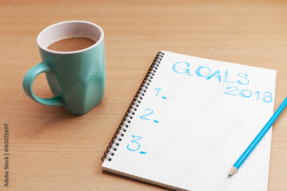 Goals 2018 text on paper note with coffee cup on business table,business plan and new year background concept. Goals 2018 text on paper note with coffee cup on business table,business plan and new year background concept.