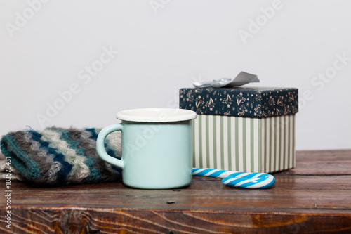 vintage bright green cup with hot tea and warm gloves on wooden table