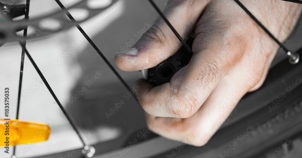 The panorama of Man pumping bicycle tyre outdoors, close-up of hands