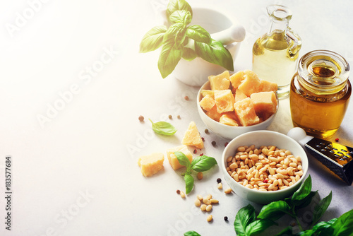 Ingredients for homemade pesto - basil, lemon, parmesan, pine nuts, garlic, olive oil and salt on white concrete background. Top view, flat lay, copyspace. Banner