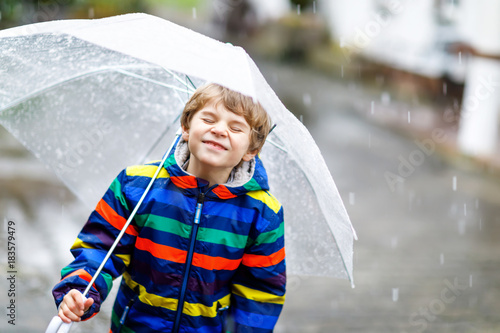 Canvastavla Little blond kid boy on way to school walking during sleet, rain and snow with a