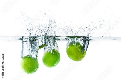 Fresh lime dropped into the water with water splash on a white background