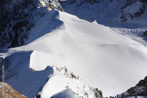 Panorama of French Alps with mountain ranges covered in snow and blue sky in winter