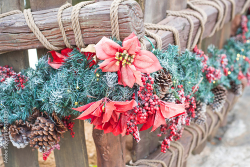 Wood fence decorated for Christmas with red flower.