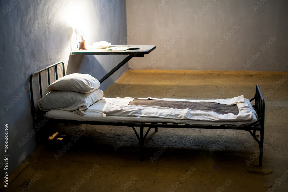 Dark prison cell with bed at night Stock Photo | Adobe Stock