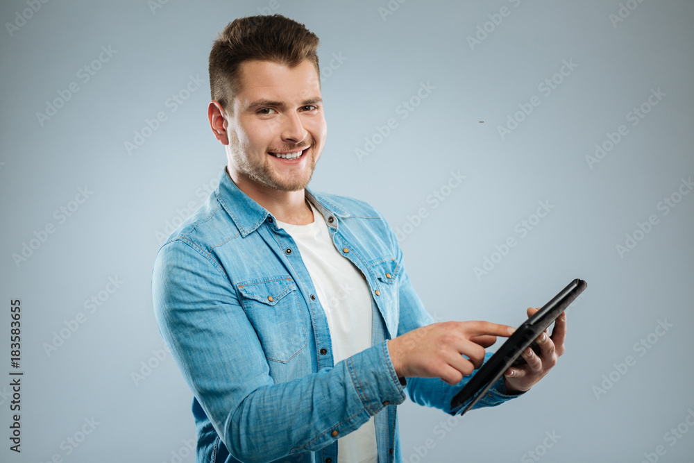 Want to test it. Attractive young man standing in semi position and smiling on camera while demonstrating his gadget Want to test it. Attractive young man standing in semi position and smiling on camera while demonstrating his gadget