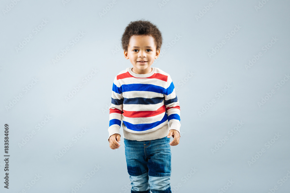 Kids emotions. Attractive kid keeping smile on his face and looking forward while working as model Kids emotions. Attractive kid keeping smile on his face and looking forward while working as model