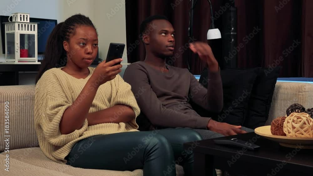 Young black woman works on smartphone and absolutely ignores her man Young black woman works on smartphone and absolutely ignores her man