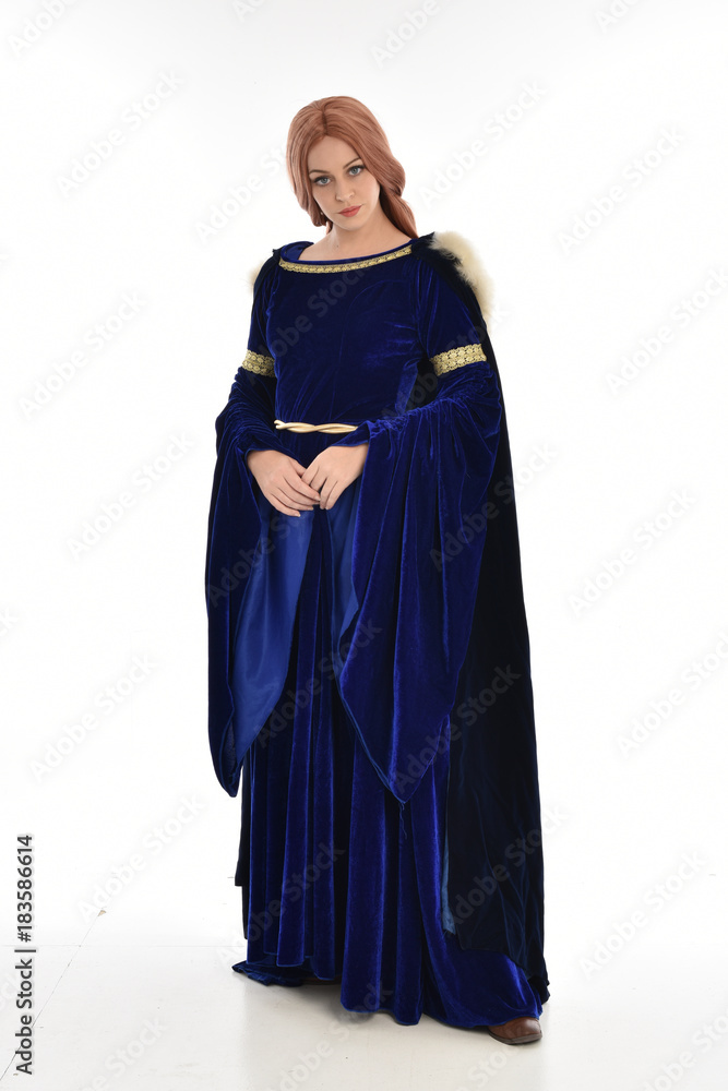 full length portrait of girl wearing long blue velvet gown and fur lined cloak, standing pose  on white background.