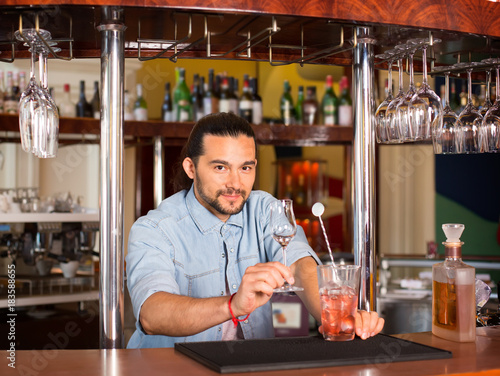 Handsome young smiling barista man offering cocktail drink.