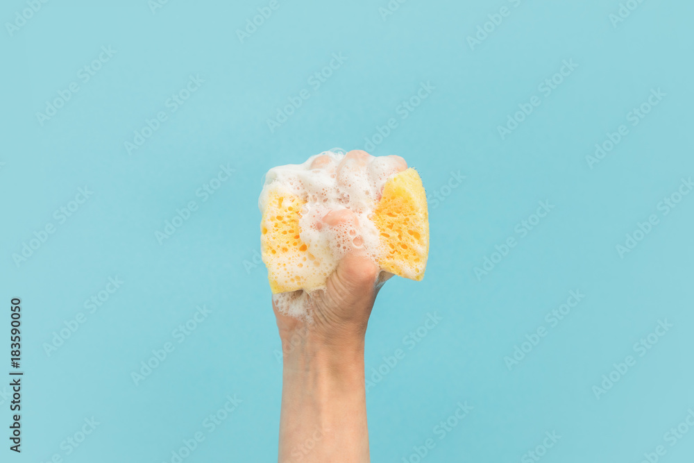 cropped view of hand holding washing sponge with foam, isolated on blue - obrazy, fototapety, plakaty 
